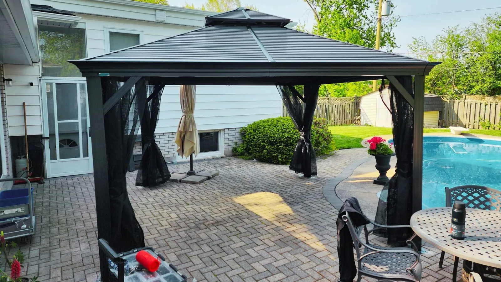 Hardtop gazebo with curtains fitted over a paver patio