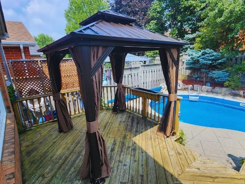 Hardtop gazebo with curtains fitted over a paver patio