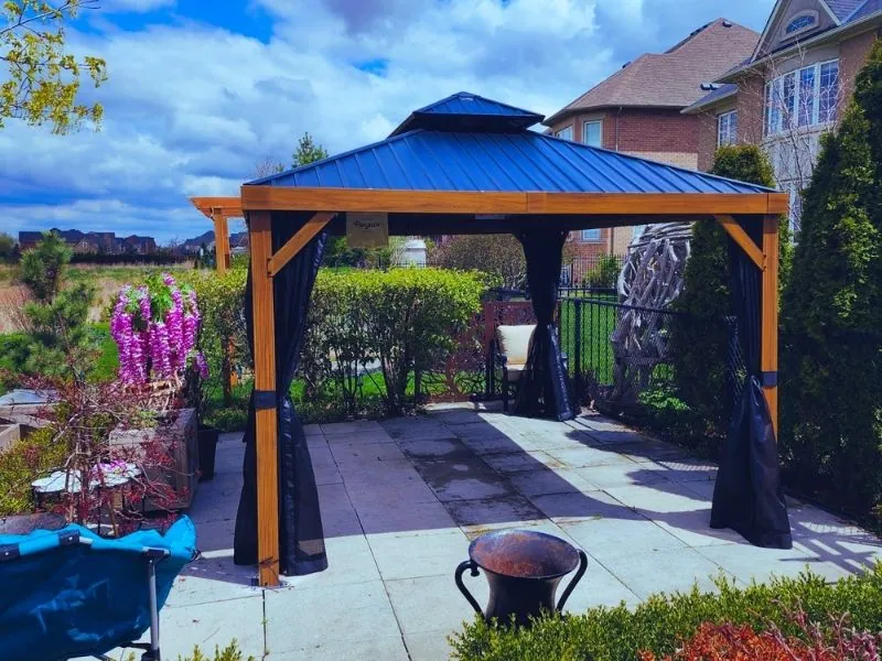 Hardtop gazebo with curtains fitted over a paver patio