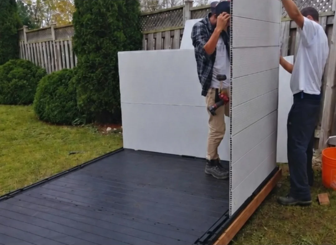 Helperama crew assembling a shed wall panel in a backyard