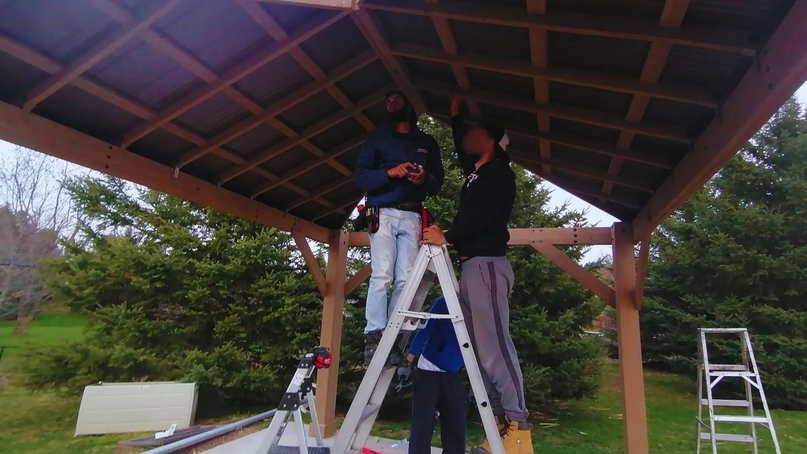 Installers fitting a gazebo roof from ladders