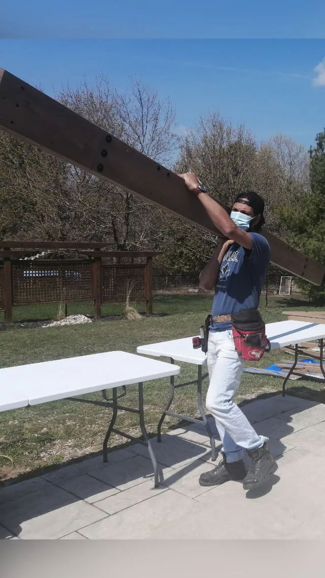 Crew member carrying a cedar beam on a gazebo build