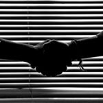 Silhouette of two people shaking hands symbolizing partnership and trust.