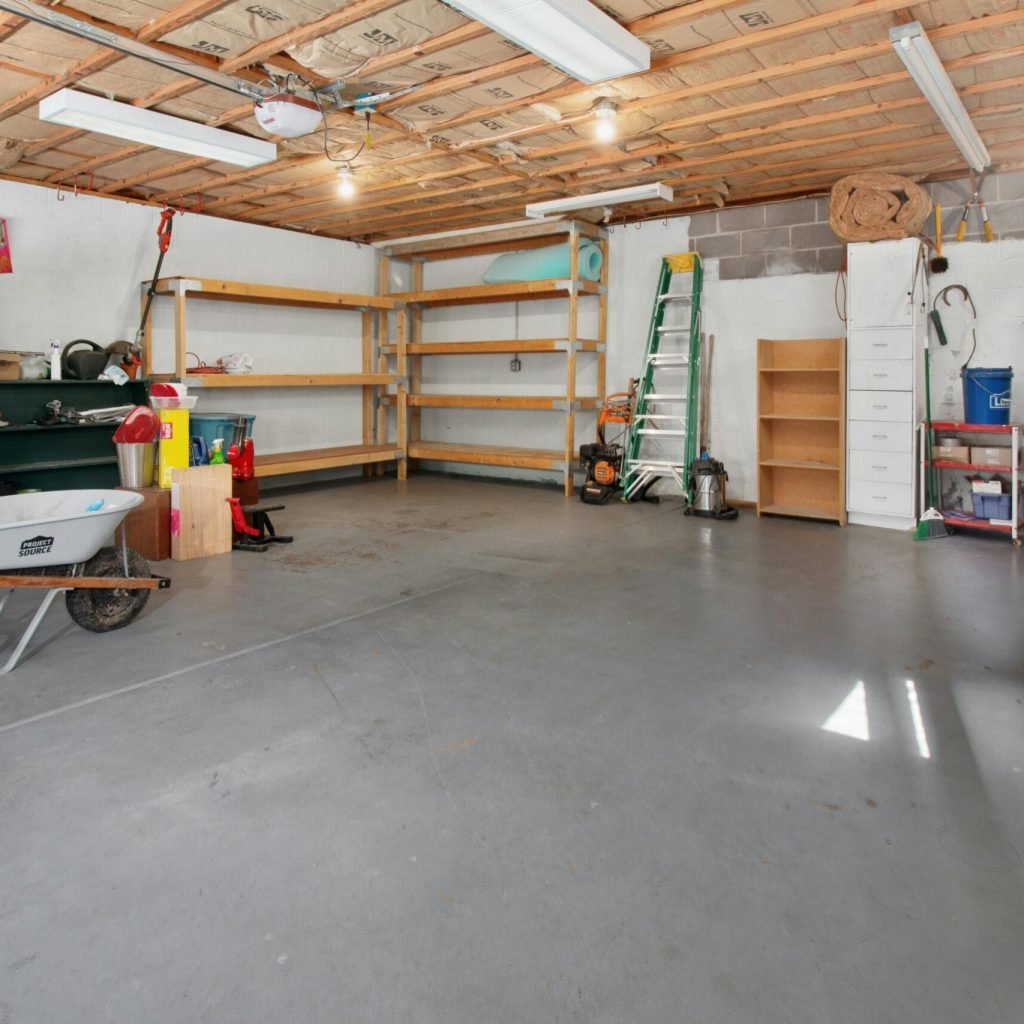 Spacious garage interior with storage shelves, tools, and a wheelbarrow, ideal for home organization.